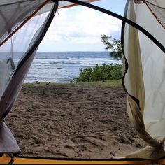 the view from inside a tent looking out at the ocean and sand on the beach