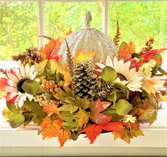 a vase filled with lots of different types of flowers and leaves on top of a window sill