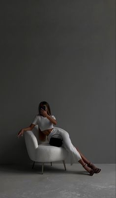 a woman is sitting on a white chair