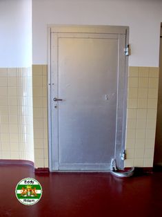 an open door in a tiled room with red flooring and white tiles on the walls