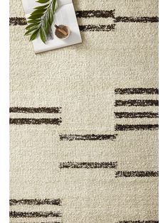 a white rug with black stripes and a green plant next to it on top of a table