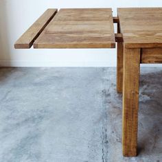 two wooden tables sitting next to each other on cement floored area with white wall in background