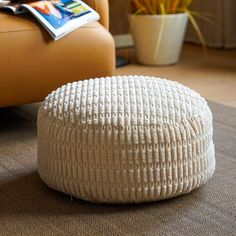 a white round ottoman sitting on top of a carpeted floor next to a couch