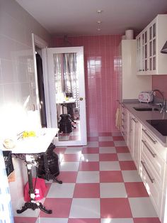 a kitchen with pink and white checkered flooring, cabinets and countertops