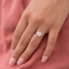 a woman's hand with a diamond ring on her left hand and pink pants