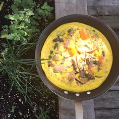 a pan filled with food sitting on top of a wooden table next to some plants