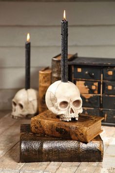 a skull sitting on top of a book next to two candles in the shape of skulls