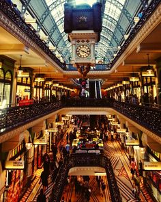 the inside of a shopping mall with people walking around and looking up at the ceiling