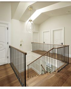 an empty room with wooden floors and white walls, two sets of stairs leading up to the second floor