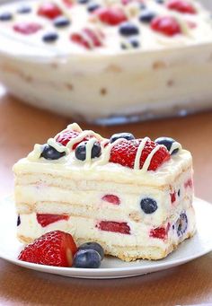 a piece of cake with berries and cream frosting sitting on top of a plate