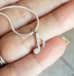 a person is holding a necklace with a musical note on it