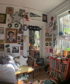 a living room filled with lots of clutter and pictures on the wall above it