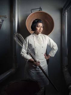 a woman in a chef's outfit is holding a whisk and looking at the camera