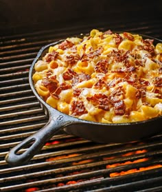 a skillet filled with macaroni and cheese on top of an outdoor grill