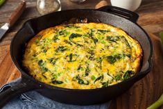 an omelet with spinach and cheese in a skillet on a cutting board