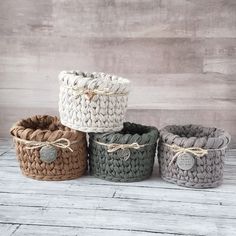 four knitted baskets sitting on top of a wooden table next to each other and tied with twine