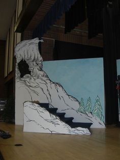 an art project is being displayed in front of a wall with mountains and trees painted on it