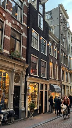 several people are walking down the street in front of some buildings with shops on each side