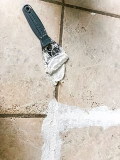 a tile floor with a mop laying on it's side next to the grout