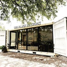 a large white shipping container sitting under a tree