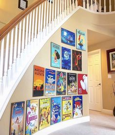 there are many books on the wall under the stairs in this house that is decorated with posters