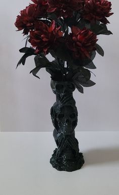 a vase filled with red flowers sitting on top of a white table next to a wall