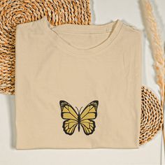 Embroidered Butterfly T-Shirt Embrace elegance and simplicity with our Embroidered Butterfly T-Shirt, a perfect blend of minimalist design and trending fashion. Design: This charming tee features a beautifully embroidered butterfly, making it a standout piece in any wardrobe. The delicate stitching captures the grace and beauty of butterflies, perfect for butterfly lovers and nature enthusiasts alike. Material: Crafted from premium, this t-shirt ensures a soft and cozy feel. It's designed for lo Butterfly Tshirt Design, Spring Butterfly Embroidered Crew Neck T-shirt, Vintage Butterfly Print T-shirt For Summer, Cute Butterfly Print Summer T-shirt, Cute Butterfly Print T-shirt For Spring, Casual T-shirt With Butterfly Print, Embroidered Butterfly, Butterfly Shirts, Embroidered Tee