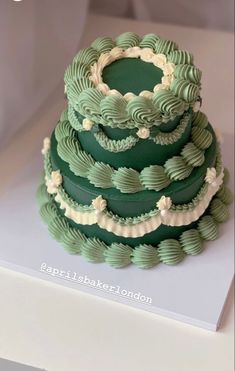 a three tiered green cake with white icing on it's top and bottom