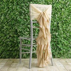 a chair with a bow tied to it sitting in front of a wall covered in greenery