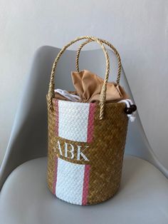 a woven basket with the initials abk on it sitting on a white plastic chair