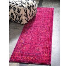 a bright pink rug is on the floor next to a black and white ottoman chair