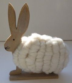 a wooden bunny rabbit sitting on top of a pile of wool