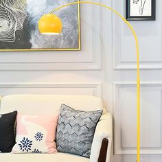 a white couch sitting under a yellow lamp next to a painting on the wall in a living room