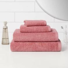 a stack of pink towels sitting on top of a bathroom counter