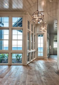 the inside of a house with large windows and doors leading to an ocean front yard