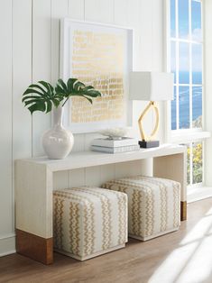 a white table with two stools and a large painting on the wall