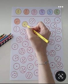 a person holding a pencil in front of a paper with numbers and circles on it