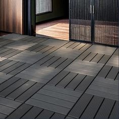 an open door with wooden flooring in front of it and a black gate on the other side