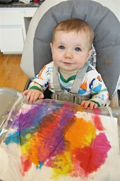 a baby sitting in a high chair with his hands on the seat cushion and looking at the camera