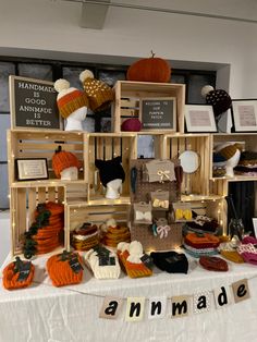 an assortment of knitted hats and sweaters displayed on a white tablecloth with wooden crates