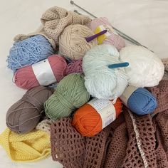 several balls of yarn and crochet hooks on a blanket