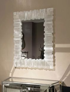 a mirror that is sitting on top of a table in front of a wall mounted sculpture