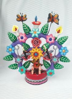 a colorful vase with flowers and butterflies on it's head, sitting in front of a white background