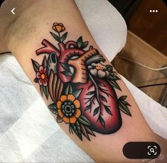 a heart tattoo with flowers and leaves on the upper half of the arm is shown