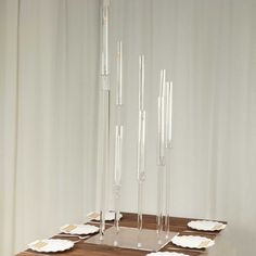 a wooden table topped with lots of white plates and silverware next to tall candles