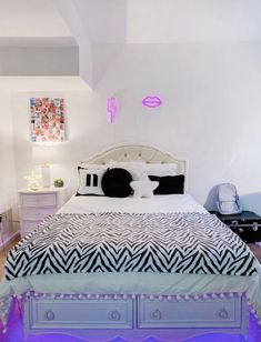 a white bed with zebra print sheets and pillows on top of it in a bedroom