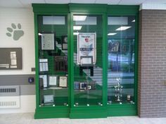 an office with green glass doors and pictures on the front wall, along with a dog paw painted on the wall