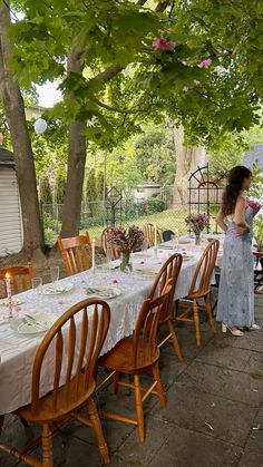 a woman standing in front of a table with flowers on it