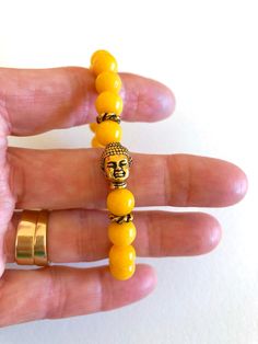 "Darling sunny yellow jade stretch bracelet with gold Buddha bead focal. Mashan jade gemstones are smooth polished 8mm rounds dyed a bright sunshine yellow color. Beautiful Buddha head focal bead is 10 x 14mm gold plated pewter made by Tierracast in the USA. Bracelet is made to order on professional stretch elastic. When selecting length please add 3/4\" to 1\" to your actual wrist measurement for a comfortable fit." Yellow Hand-strung Jewelry For Meditation, Yellow Beaded Jewelry For Meditation, Spiritual Yellow Jewelry With 8mm Beads, Adjustable Yellow Spiritual Bracelets, Adjustable Spiritual Yellow Bracelets, Spiritual Yellow Beaded Bracelets With 8mm Beads, Yellow Spiritual Hand-strung Beaded Bracelets, Spiritual Yellow Hand-strung Beaded Bracelets, Handmade Gold Stretch Bracelet For Meditation