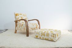 a chair and footstool sitting on top of a rug in front of a white wall